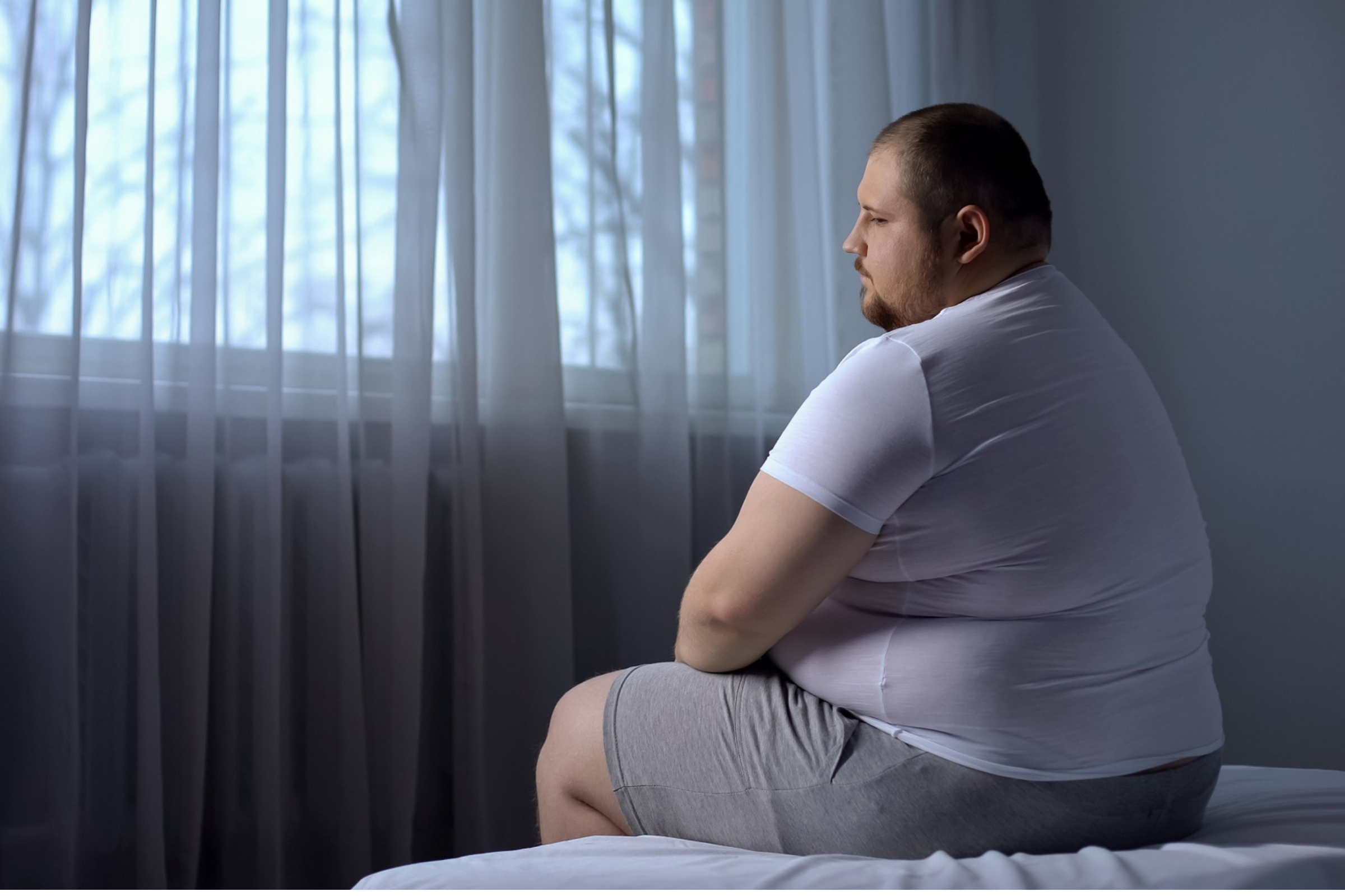 obese man sat on bed