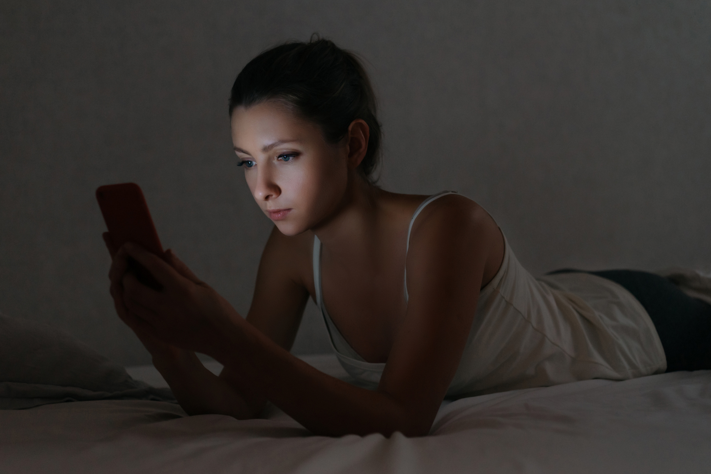 woman looking at phone in bed